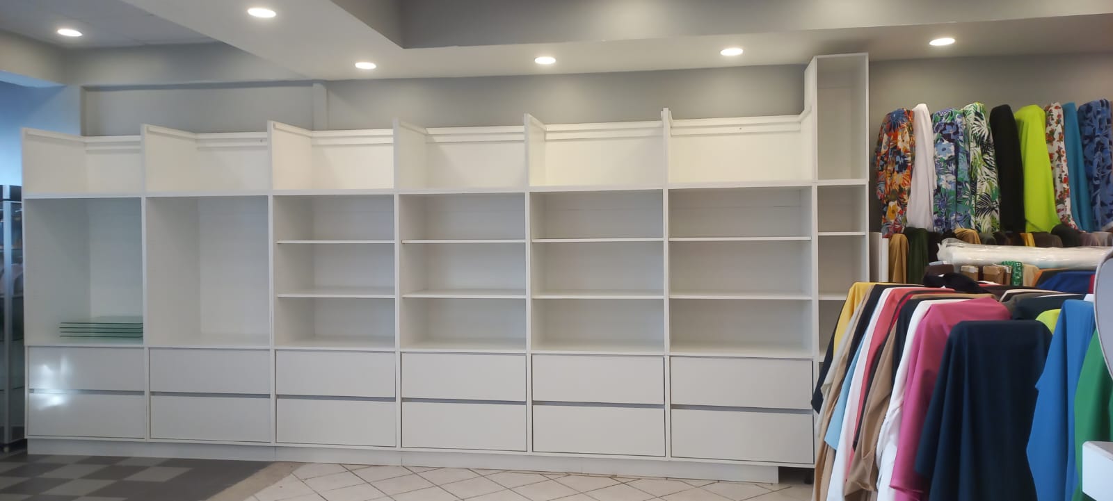 Retail shop shelving wall with clothing rail