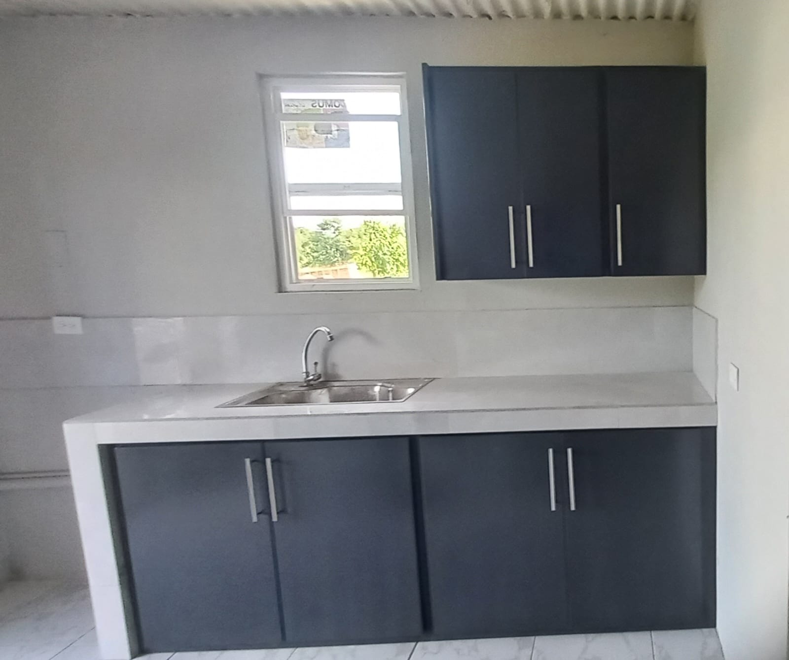 Kitchenette with dark cabinetry and stainless sink
